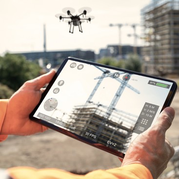 A drone surveying a building site, its live view on a tablet